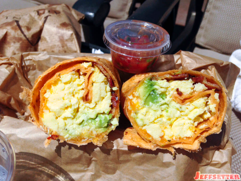 Tasty bacon, egg, avocado, cheese breakfast burrito with salsa